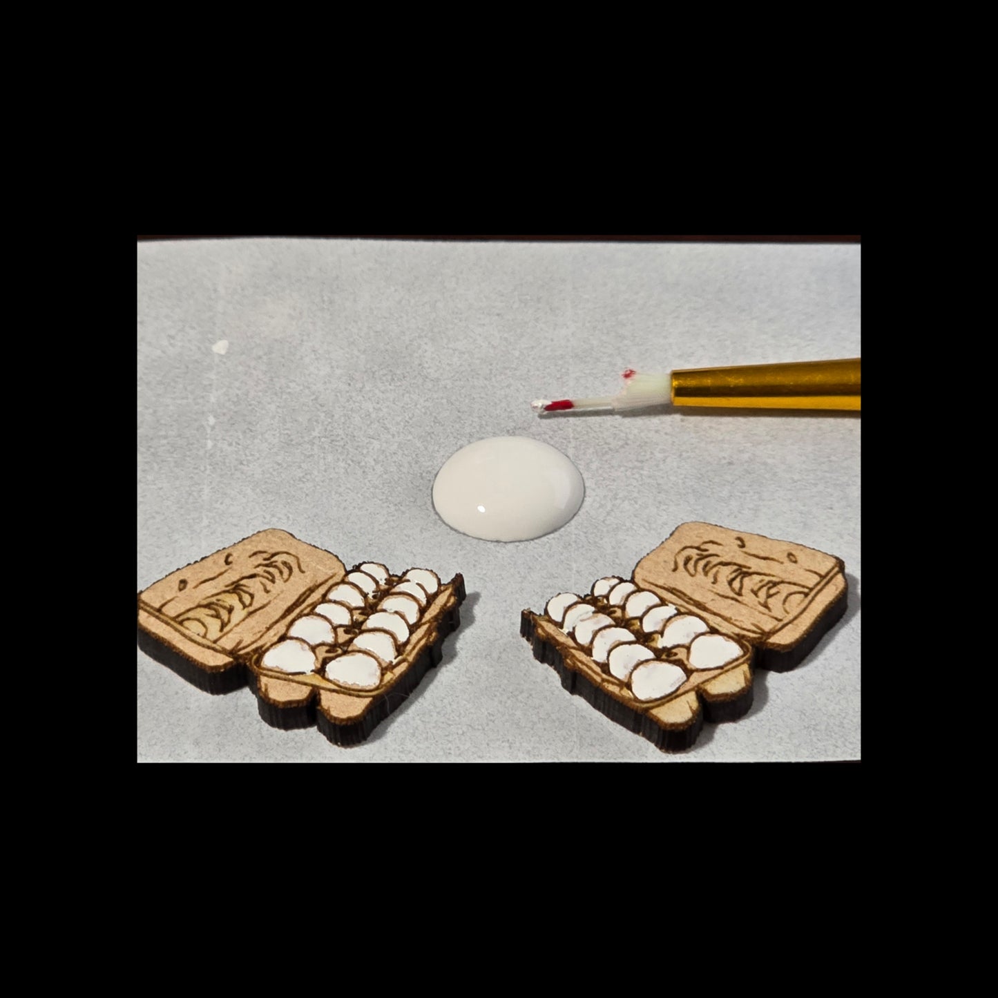 Two wooden egg crates with eggs and a dropper with red liquid on a gray background