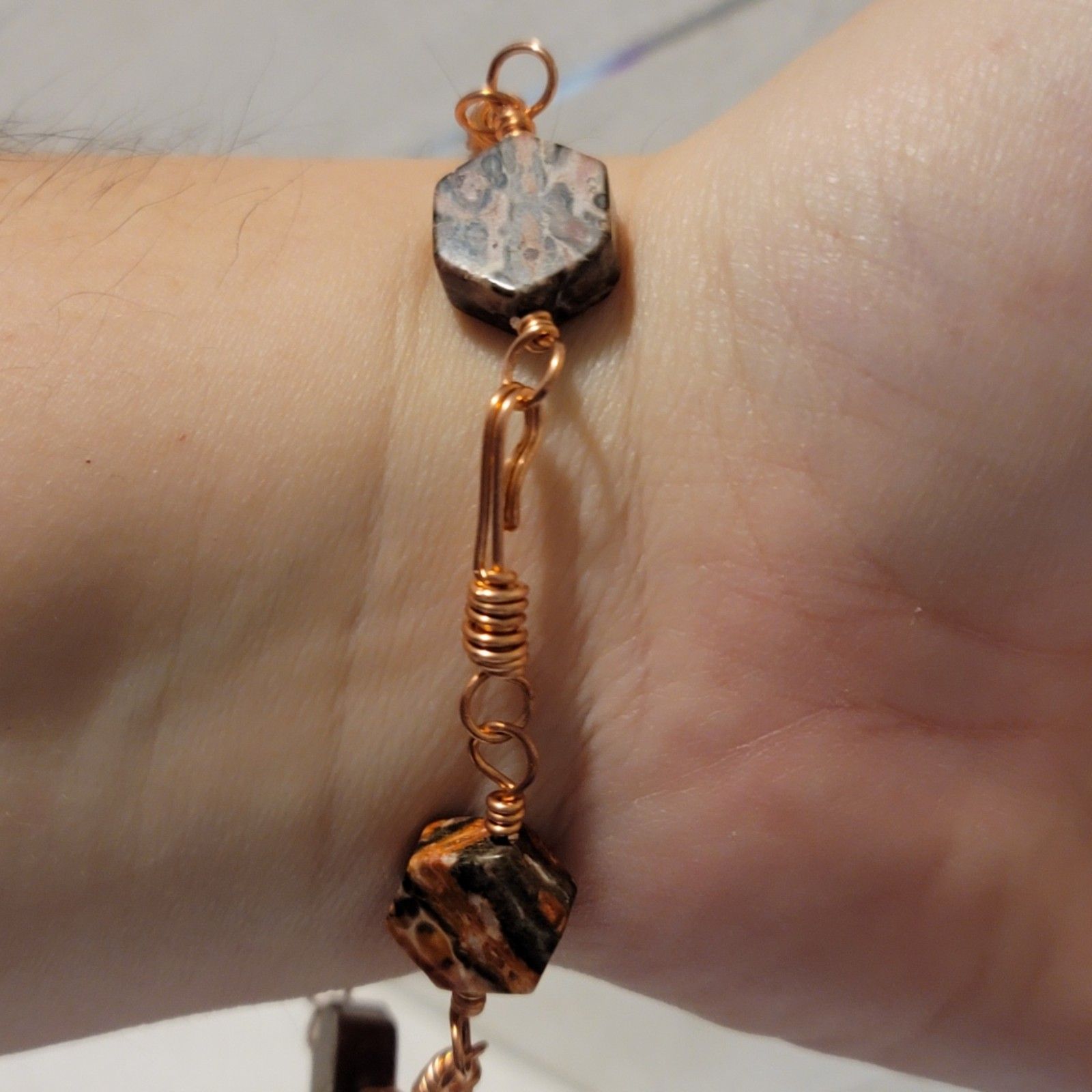 Close-up of a copper bracelet on a wrist with a neutral background