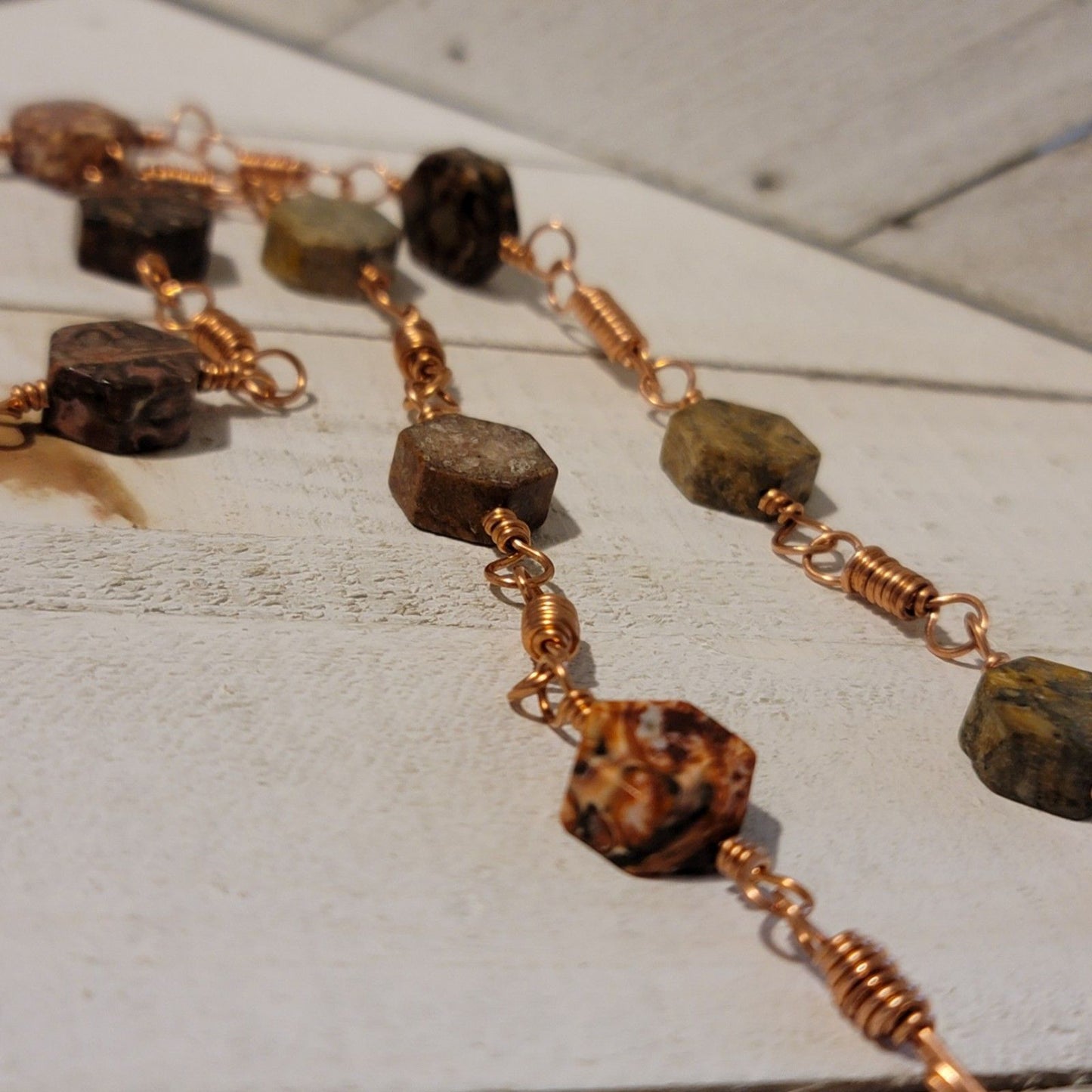 Necklace with stone beads and copper chain on a wooden surface