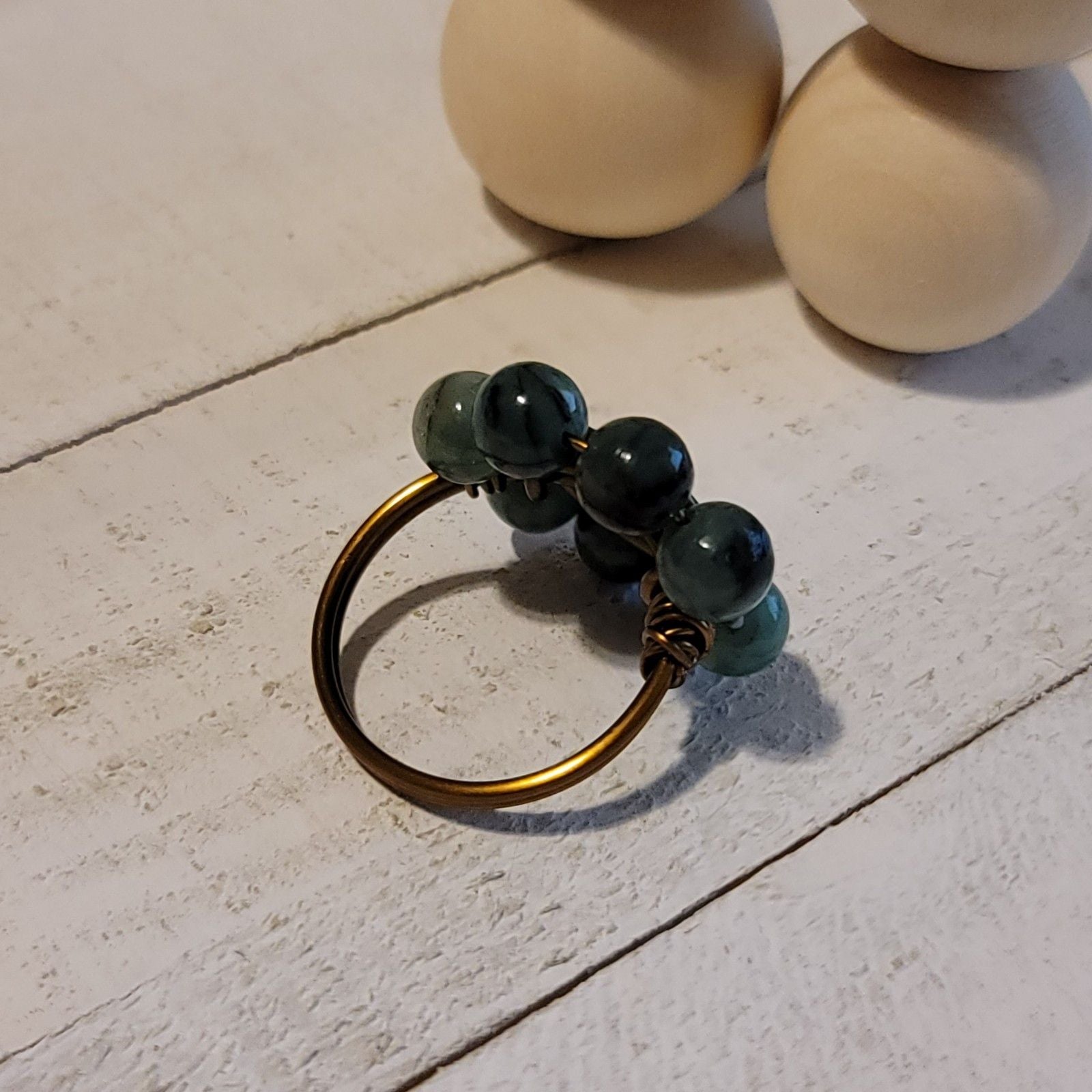 Gold ring with green beads on a light stone surface