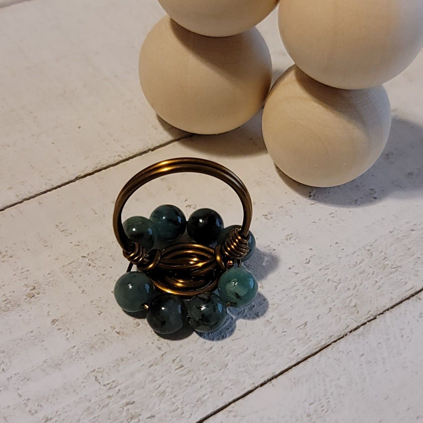 Small decorative basket with green beads on a light stone surface