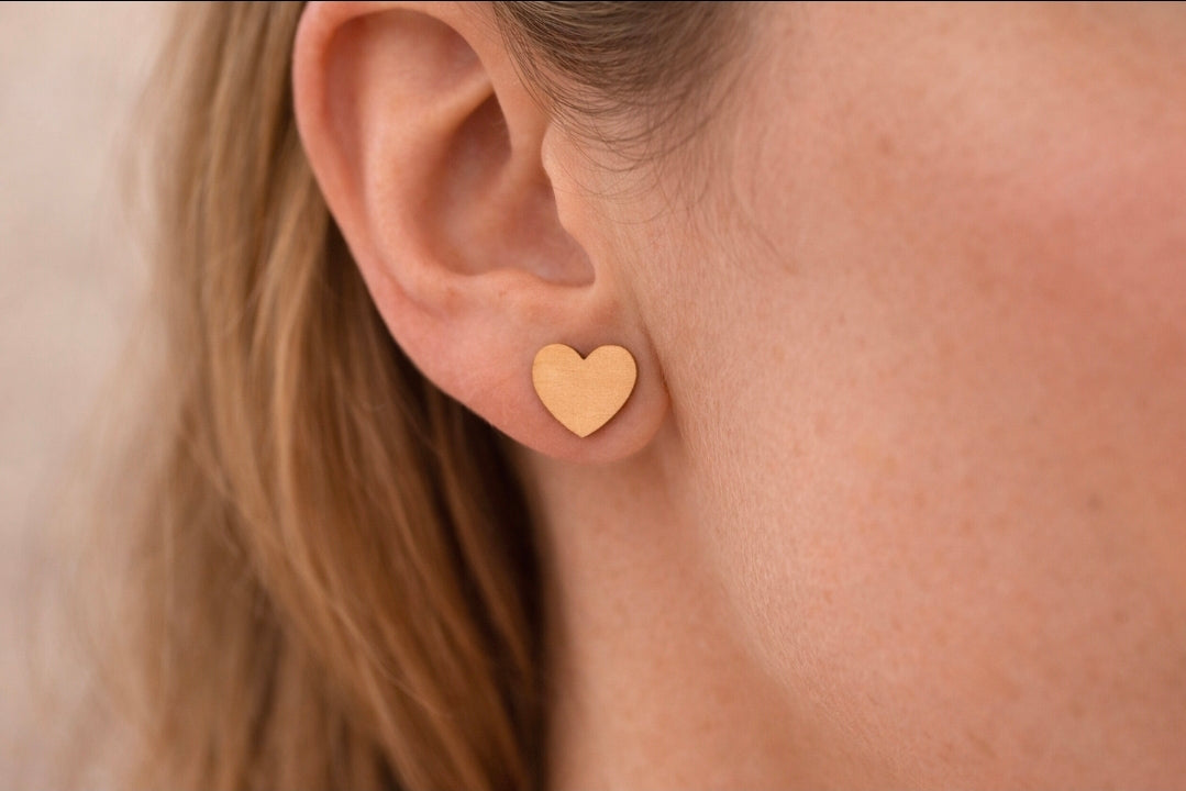 Close-up of a person wearing a gold heart-shaped earring.