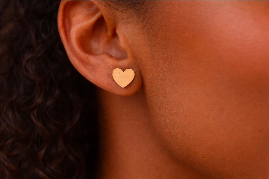 Close-up of an ear wearing a gold heart-shaped earring.