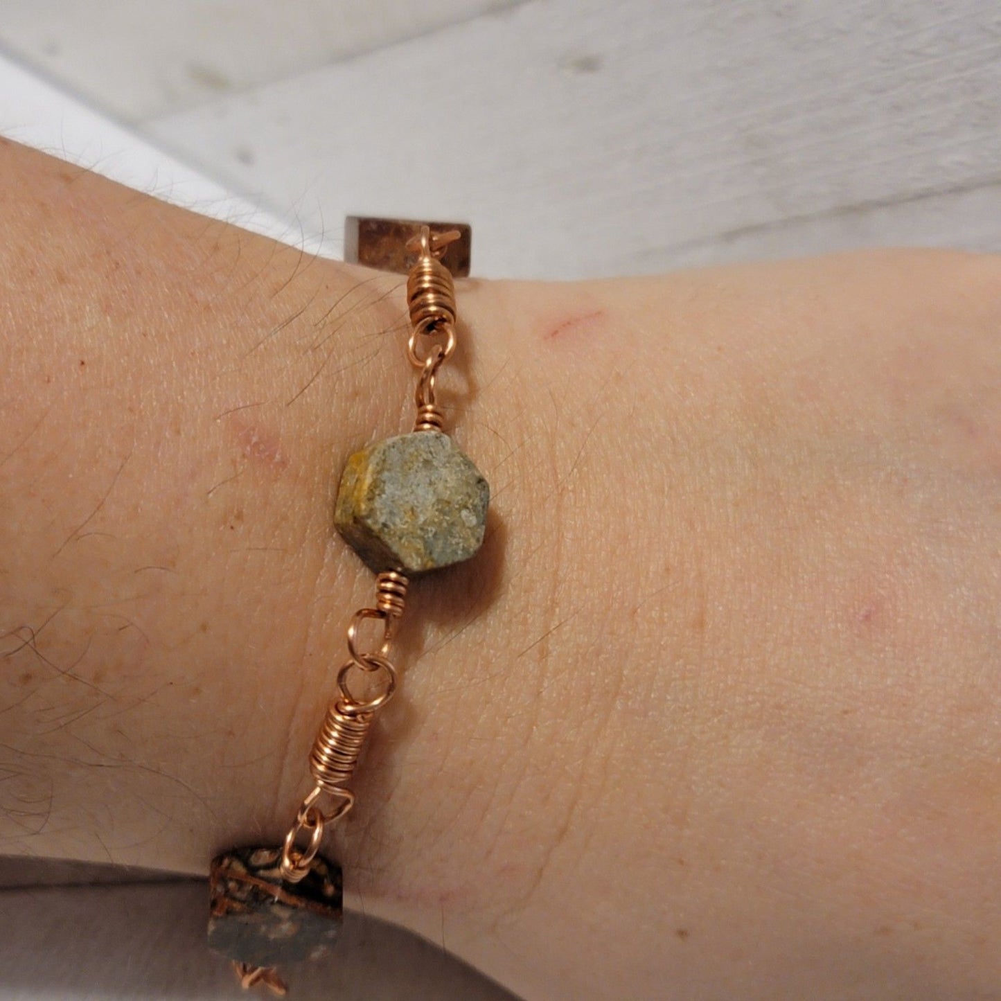 Bracelet with natural stone beads on a wrist against a neutral background