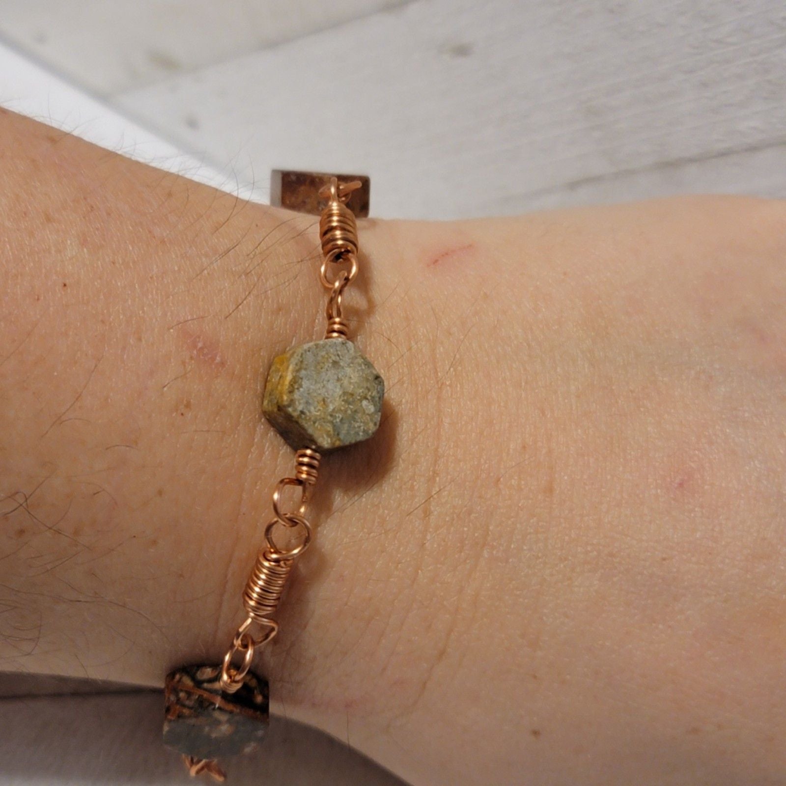 Bracelet with natural stone beads on a wrist against a neutral background