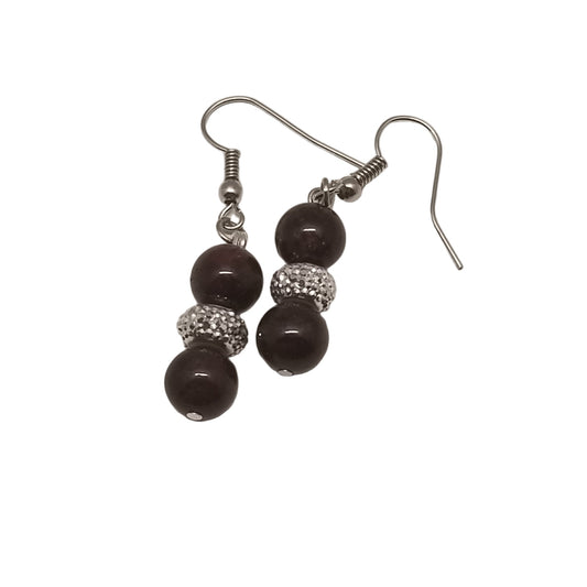 Pair of earrings with dark beads and silver hooks on a light gray background