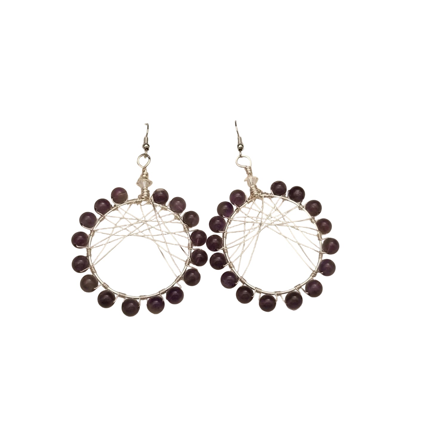Pair of silver earrings with purple beads on a beige fabric background