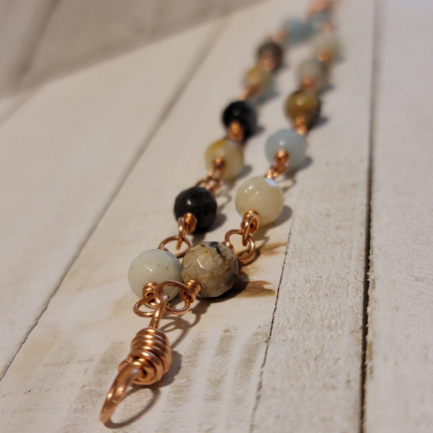 Necklace with beads and a copper spiral pendant on a wooden surface
