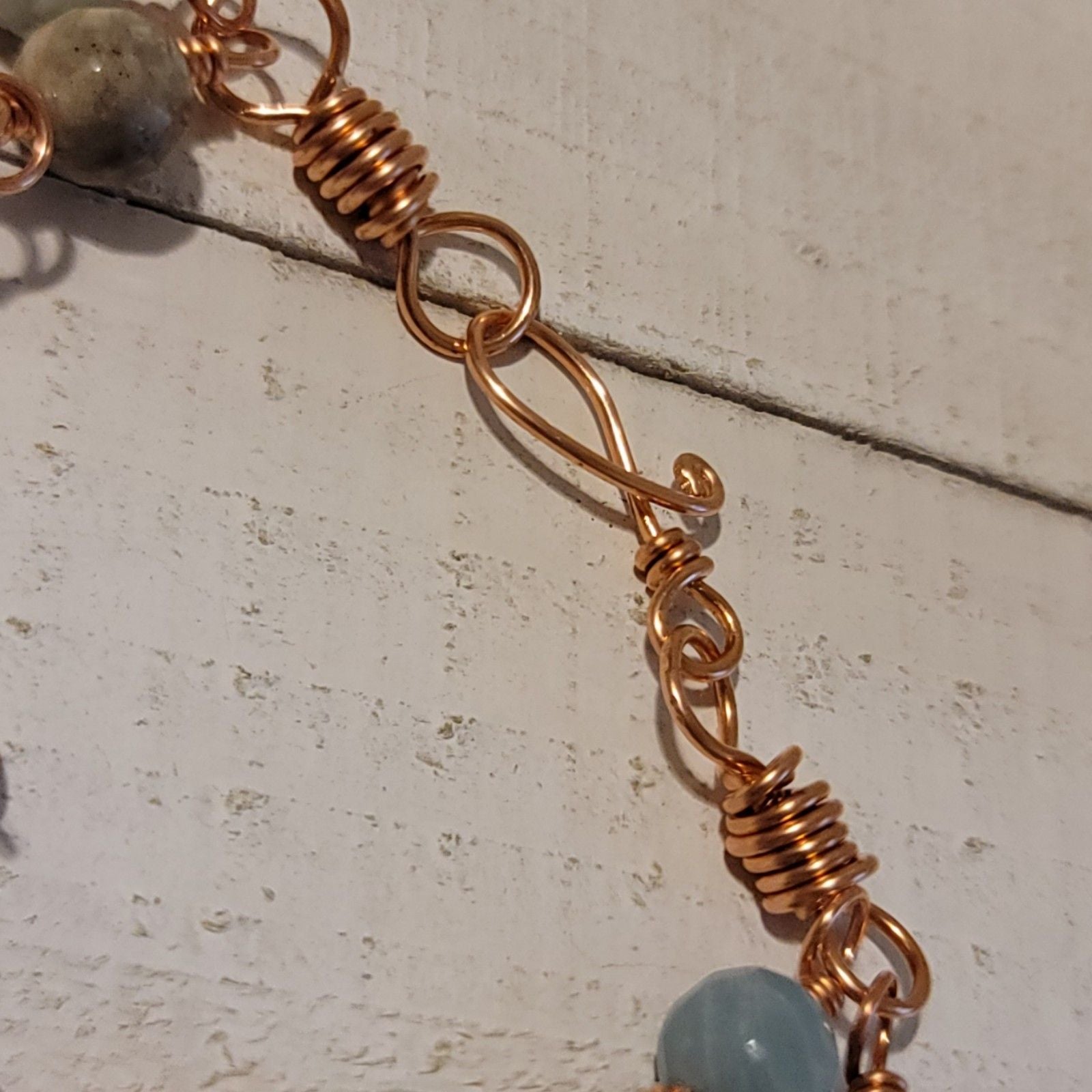 Close-up of a copper bracelet with beads on a textured surface