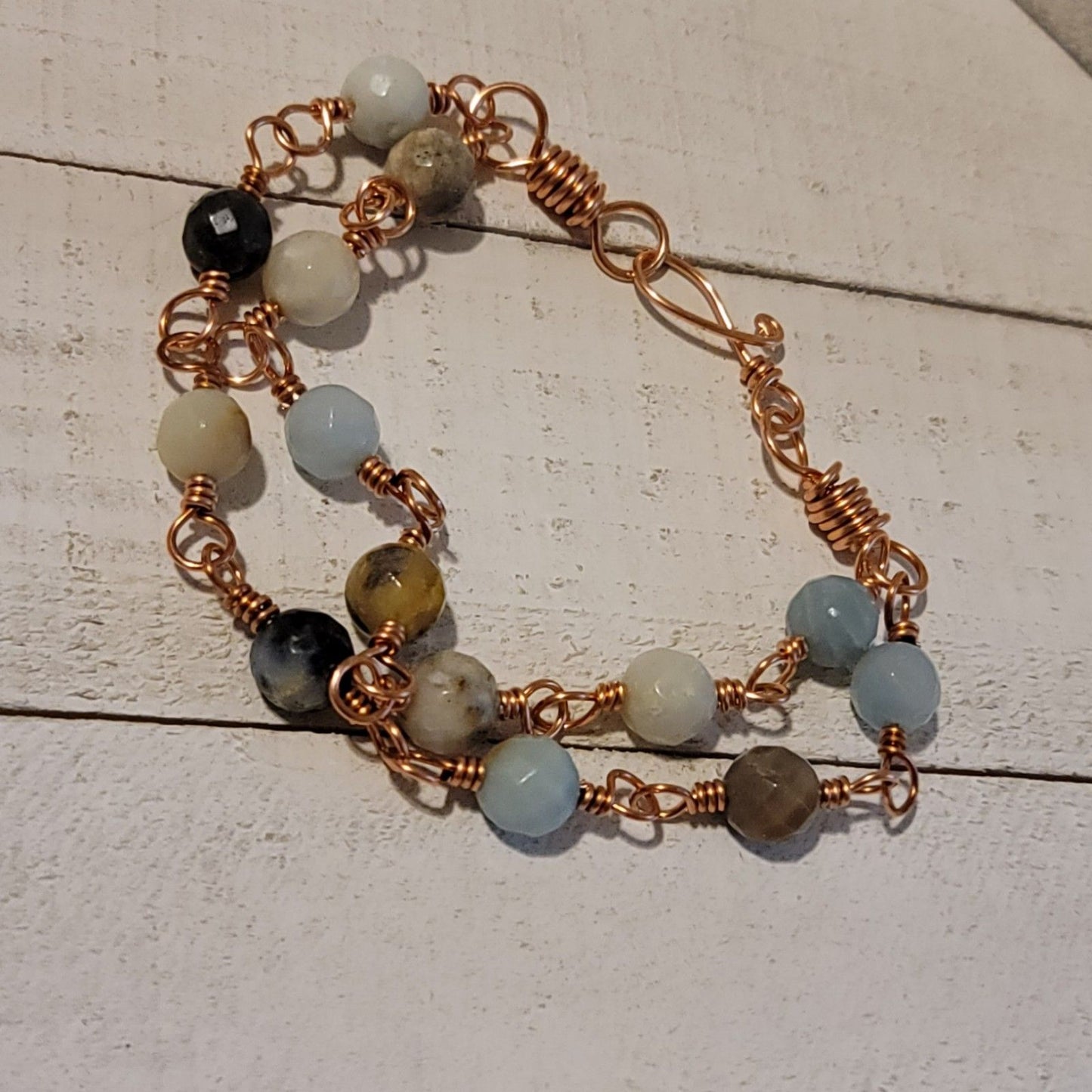 Bracelet with beads and copper wire on a wooden surface
