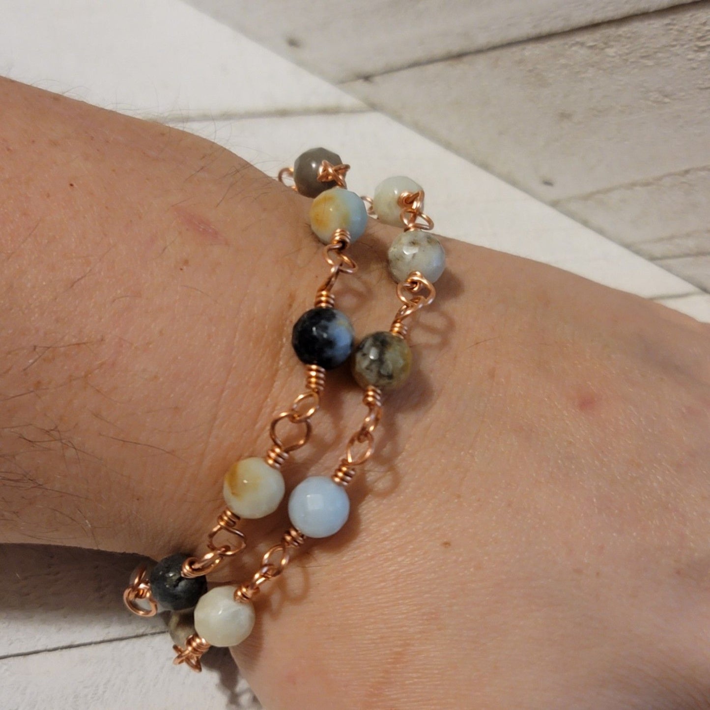 Bracelet with multicolored beads on a wrist against a light wooden background