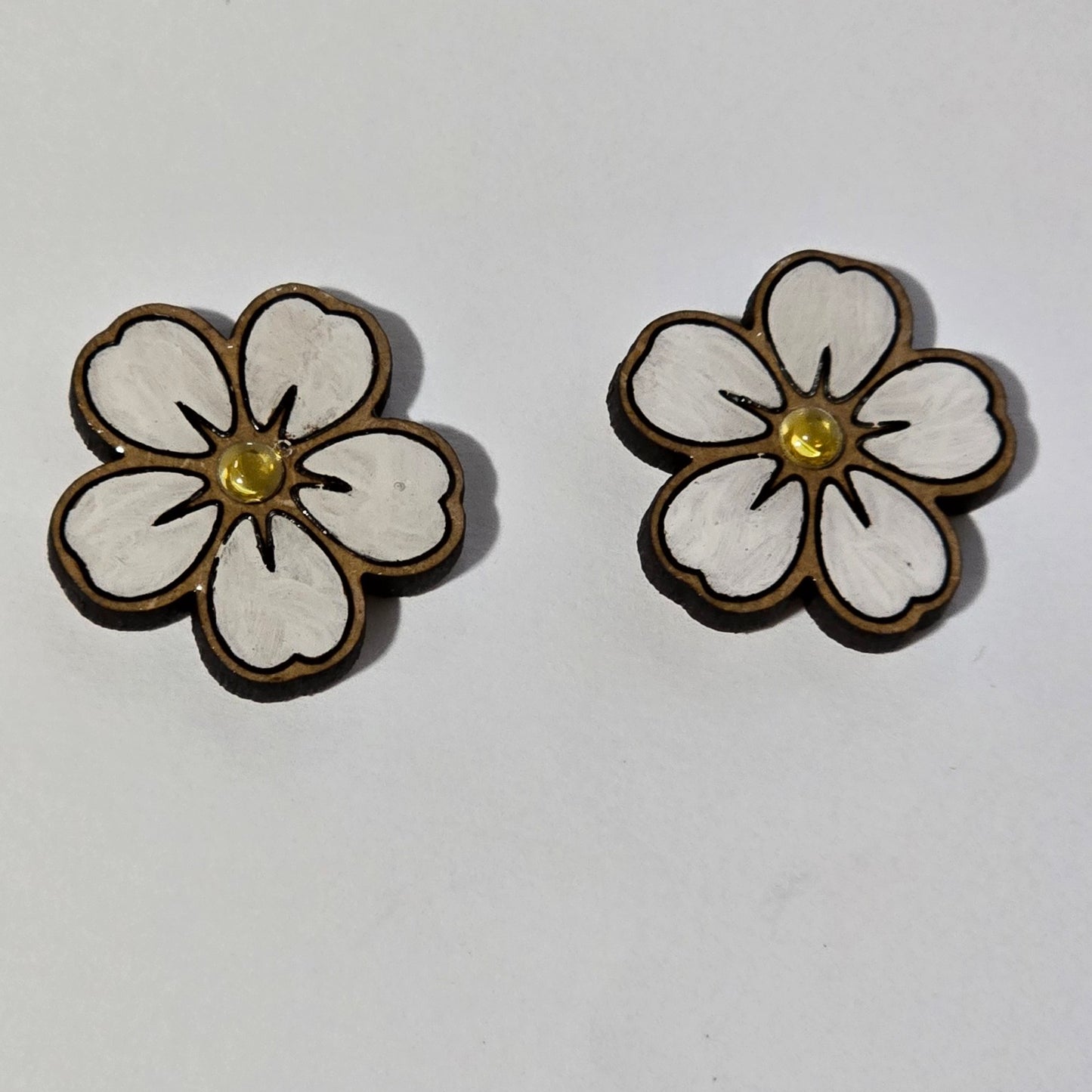 Flower-shaped earrings with white centers and gold accents on a light gray background