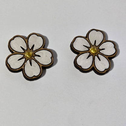 Flower-shaped earrings with white centers and gold accents on a light gray background