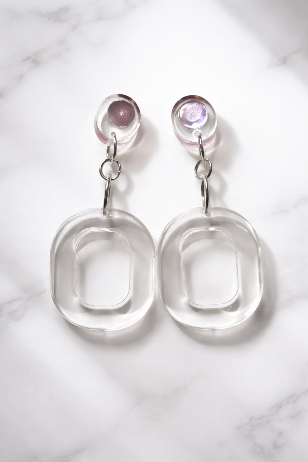 Silver earrings with round gemstones on a marble background
