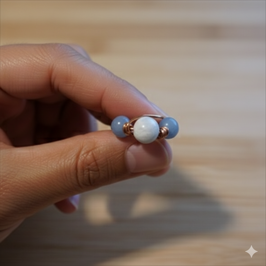 Hand holding a small bracelet with blue and white beads on a wooden surface