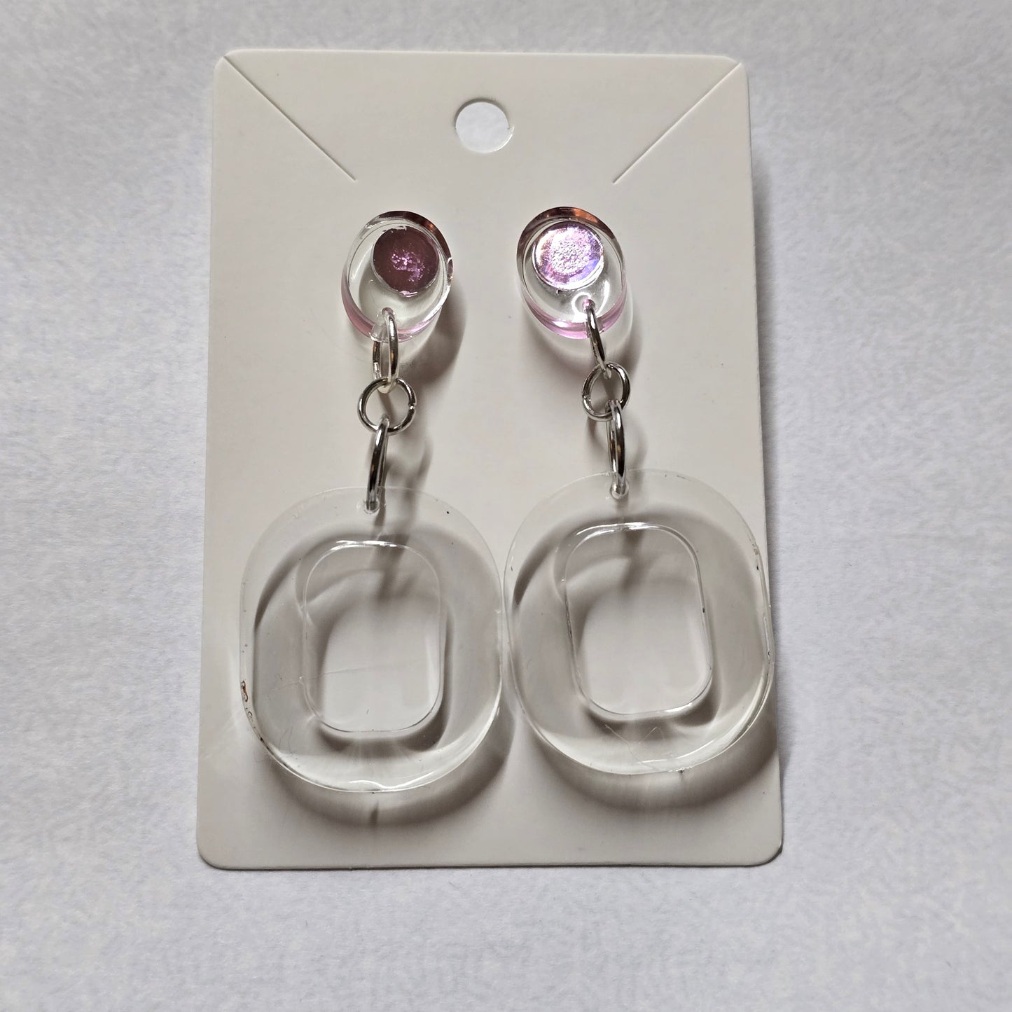 Pair of silver hoop earrings with pink gemstones on a white card.