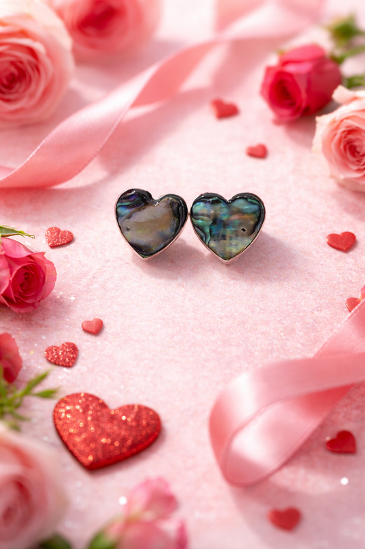 Heart-shaped earrings on a pink fabric background with roses and heart-shaped decorations.