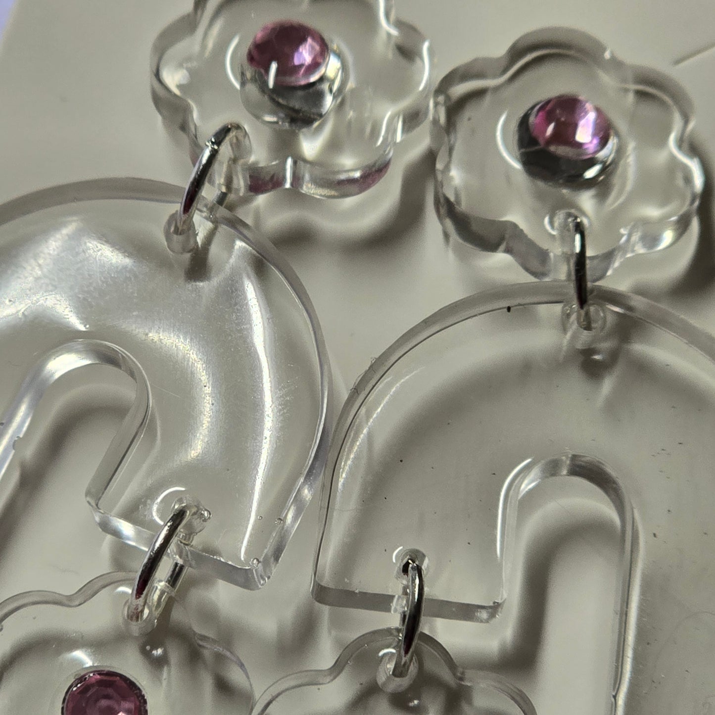 Close-up of clear earrings with pink gemstones on a white background
