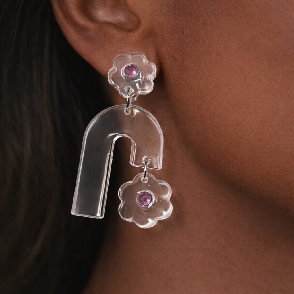 Silver earrings with pink gemstones worn by a person.