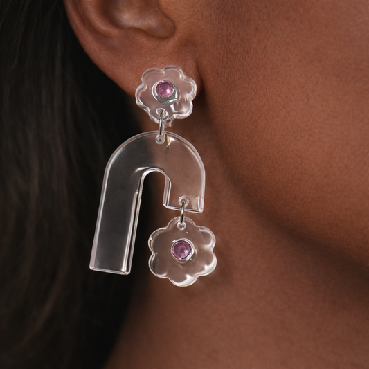 Silver earrings with pink gemstones worn by a person.