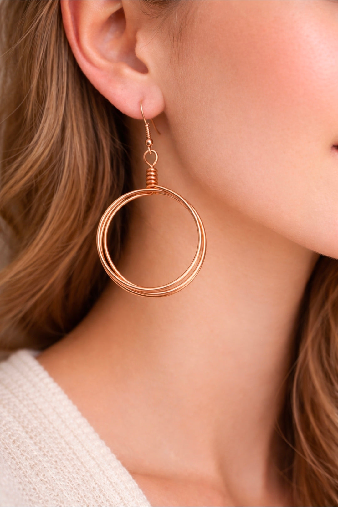 Close-up of a person wearing a rose gold hoop earring.