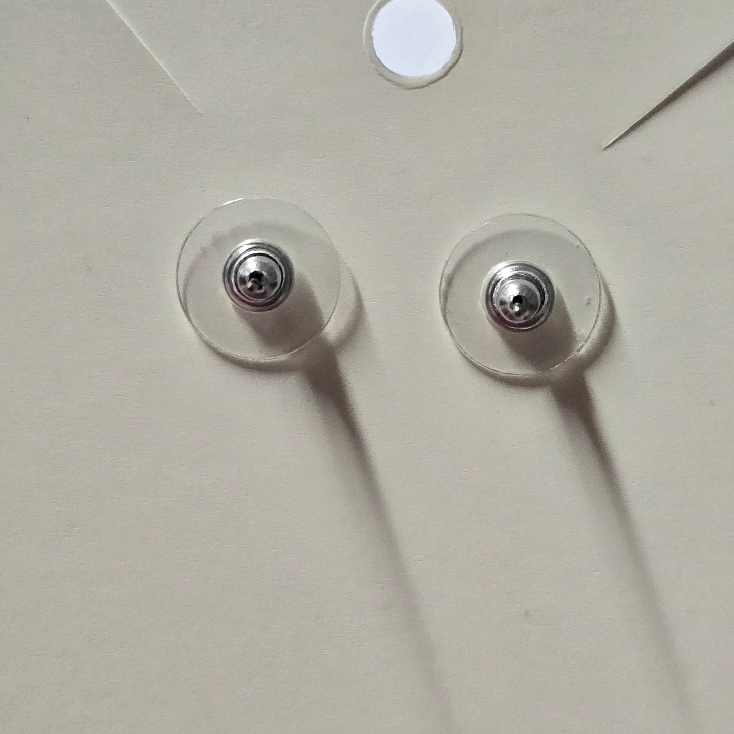 Two clear adhesive pads with metal centers on a white surface