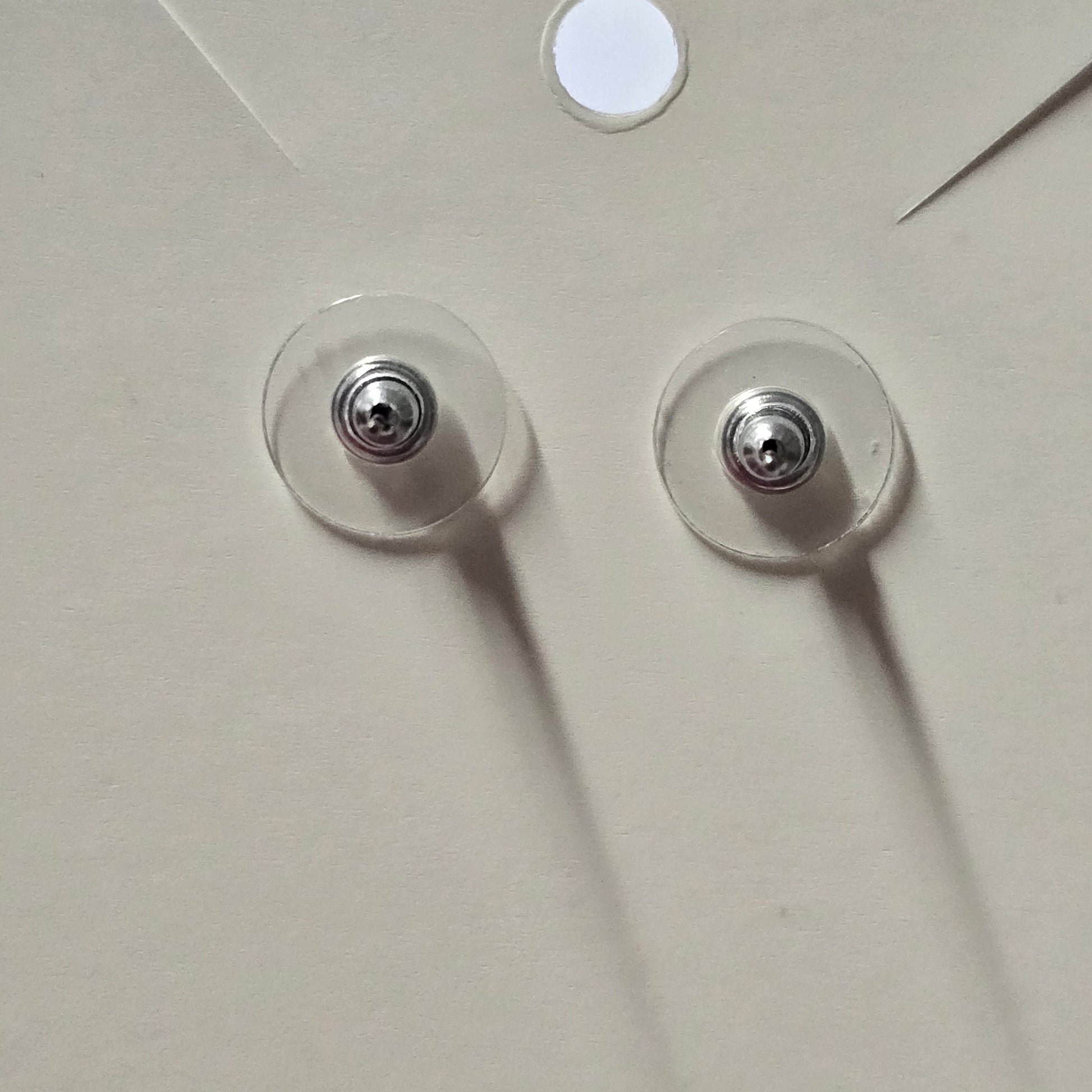 Two clear adhesive pads with metal centers on a white surface